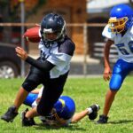 Youth football players in action during a game on a sunny day.