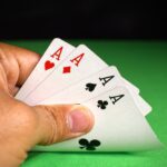 Hand holding four aces from a deck of cards.